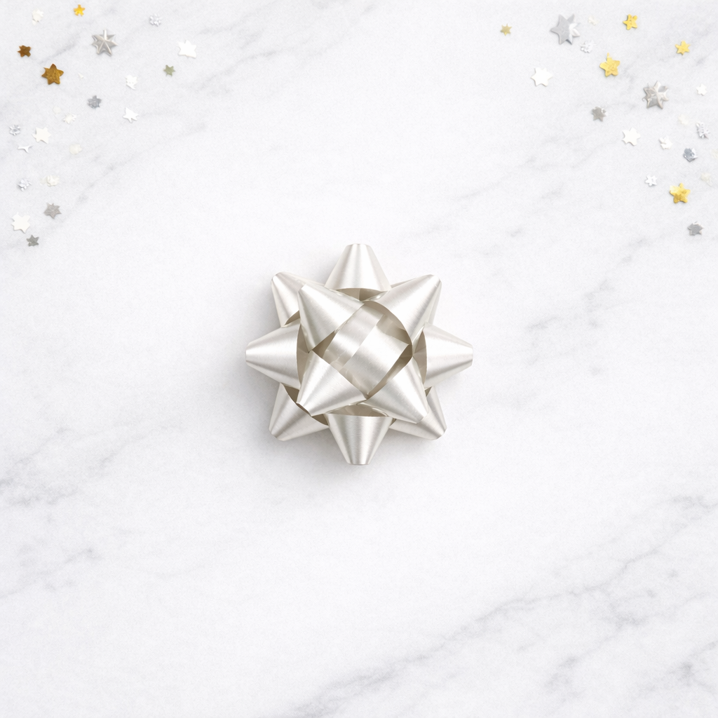 Silver gift bow on a white marble surface with star-shaped confetti.