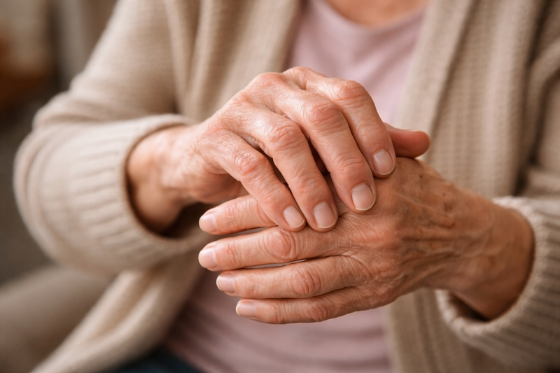 Close-up of an elderly person's hands clasped together with arthritis and dexterity issues.