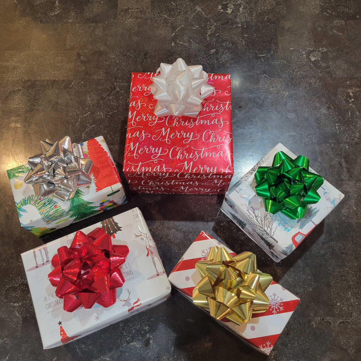 Five Christmas presents with colorful bows on a dark textured surface